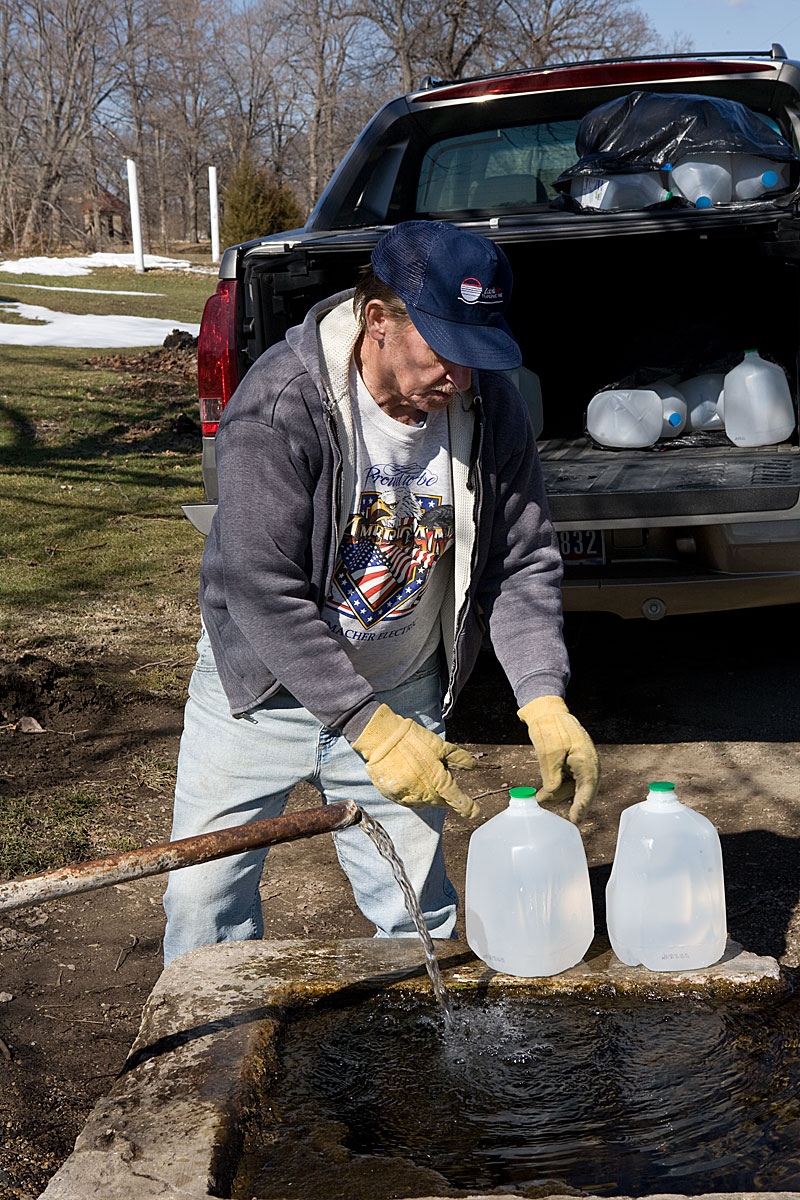 Man filling water jugs at the Tree Spring